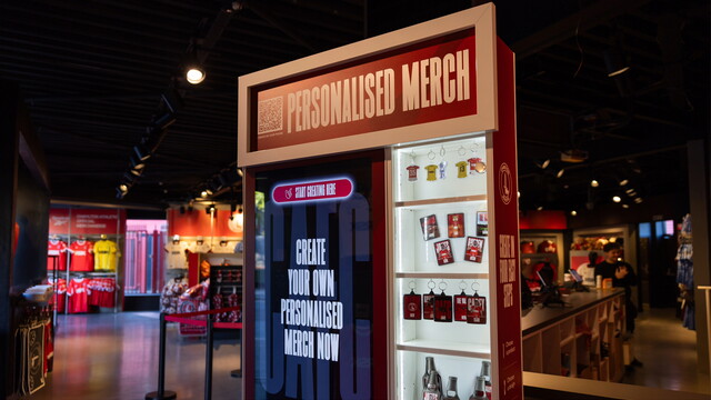 Red-and-white personalised merchandise vending machine with a red sign and glass display
