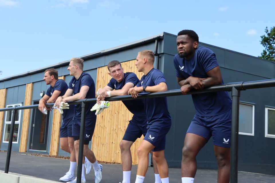 Alex Gilbey, Craig MacGillivray, Nathan Harness, Charles Clayden and Diallang Jaiyesimi look out onto the training pitches at Sparrows Lane