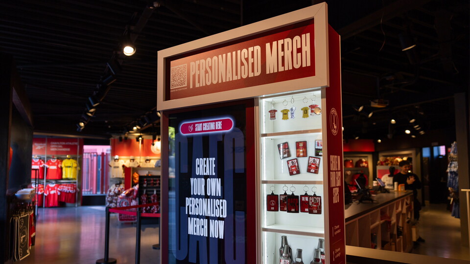 Red-and-white personalised merchandise vending machine with a red sign and glass display