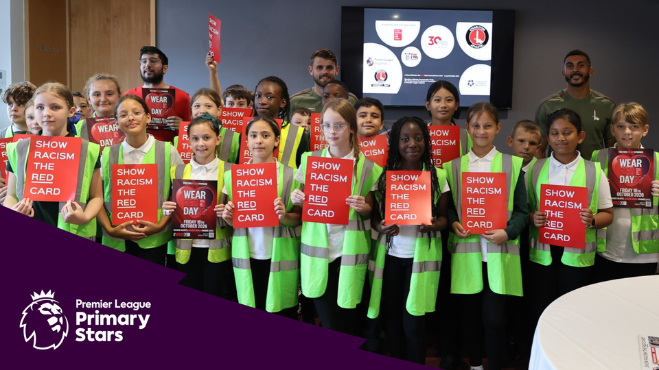 Children in high-visibility vests stand in a row, holding red signs